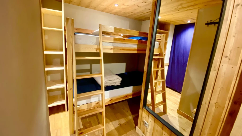 Chambre avec deux lits simples et miroir, espace fonctionnel idéal pour un séjour en appartement à la montagne
