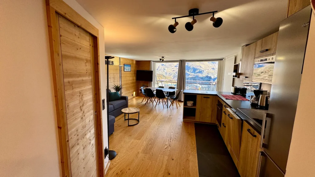Salon avec canapé et cuisine ouverte offrant une vue sur la montagne, espace lumineux et convivial