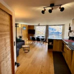Salon avec canapé et cuisine ouverte offrant une vue sur la montagne, espace lumineux et convivial
