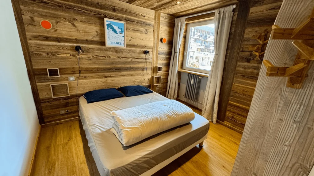 chambre appartement tignes avec lit double et décoration bois vue station