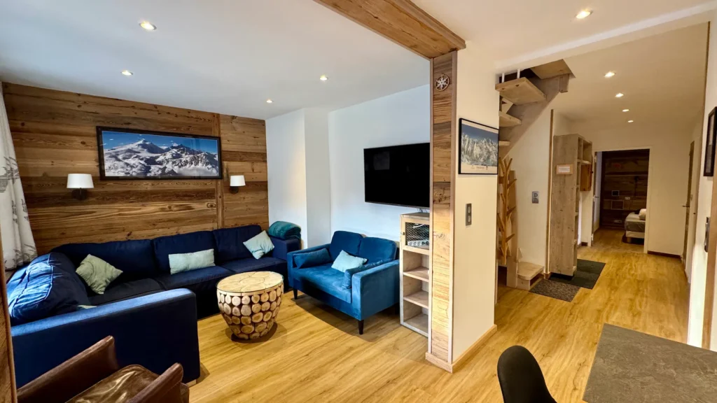 grand salon cosy avec canapé bleu et tv appartement à tignes style chalet