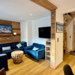 grand salon cosy avec canapé bleu et tv appartement à tignes style chalet
