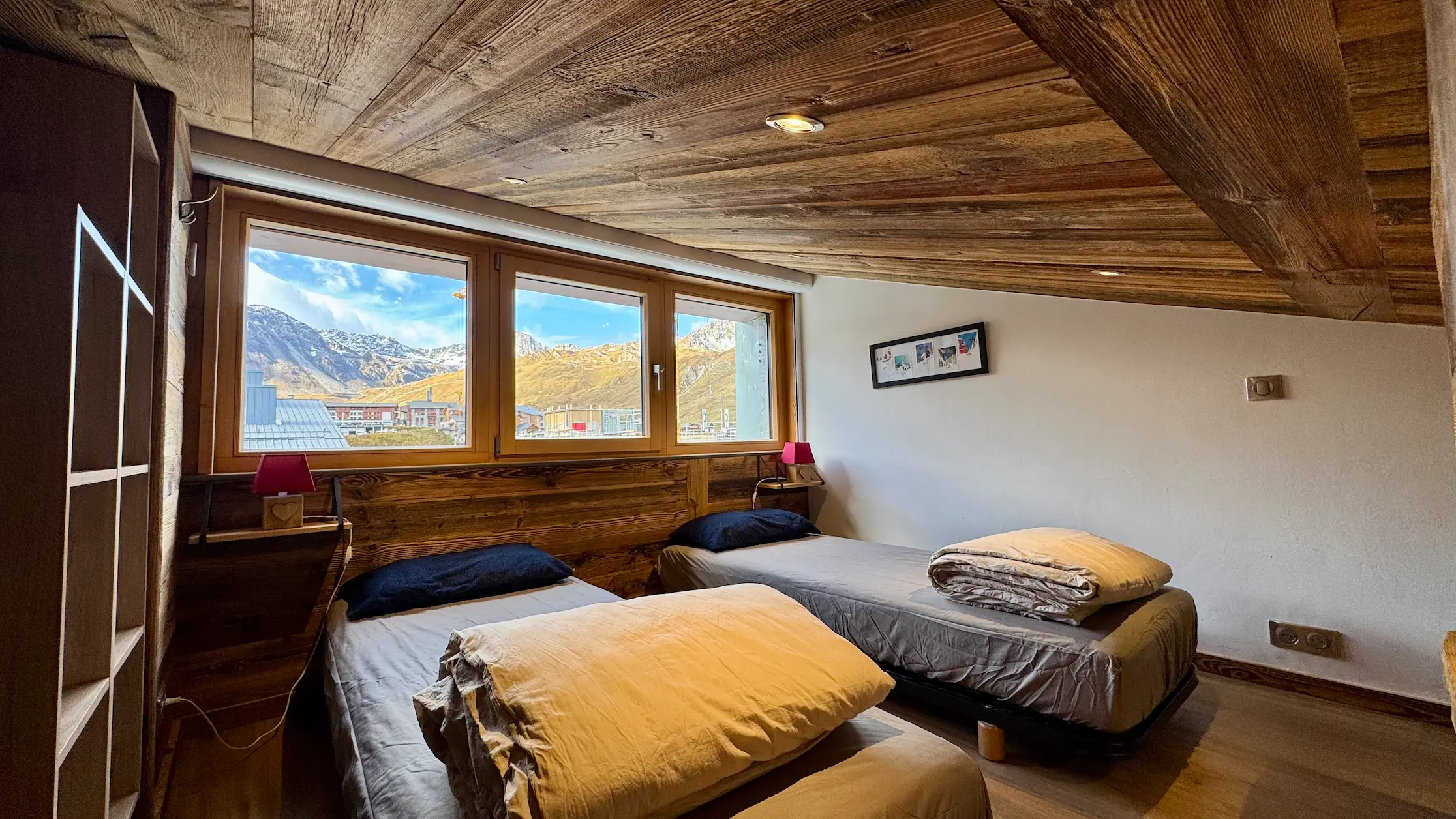 Chambre avec deux lits simples vue sous un autre angle, fenêtre offrant une vue sur la montagne et ambiance lumineuse et apaisante