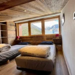 Chambre avec deux lits simples et fenêtre donnant sur une vue sur la montagne, espace lumineux et calme idéal pour un séjour reposant