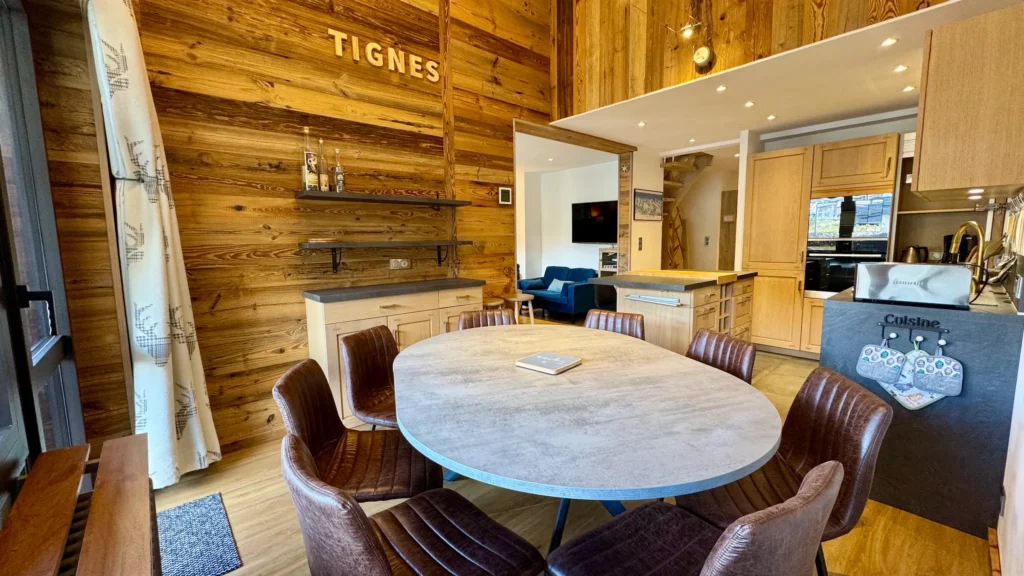 grand salon avec table ronde et cuisine ouverte dans appartement à tignes