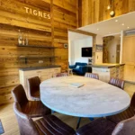 grand salon avec table ronde et cuisine ouverte dans appartement à tignes