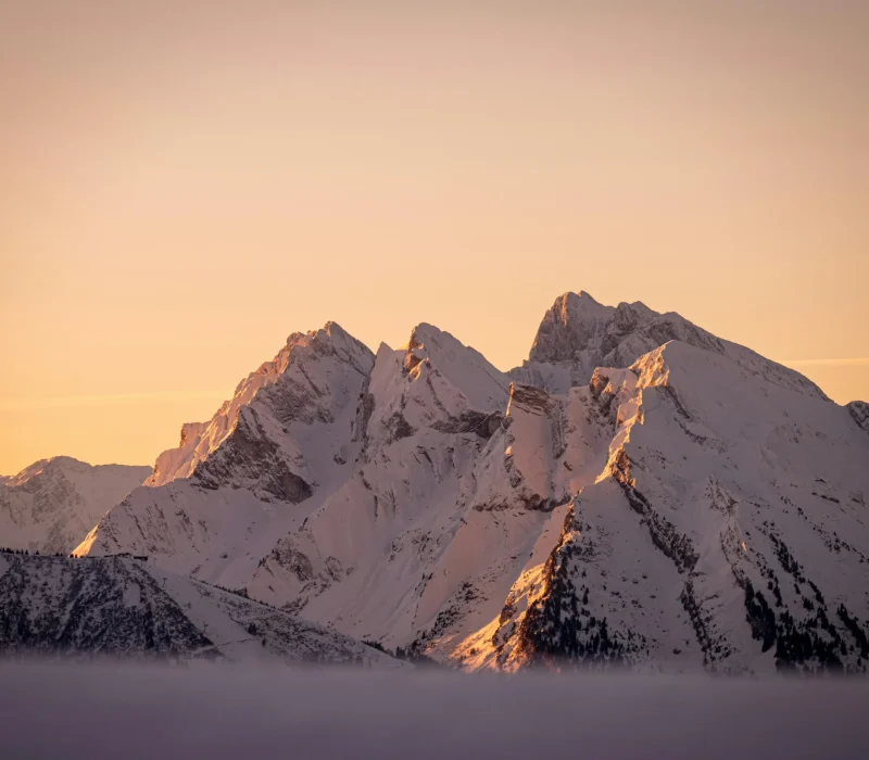 Paysage de montagne enneigée au coucher de soleil avec lumières chaudes sur les sommets alpins